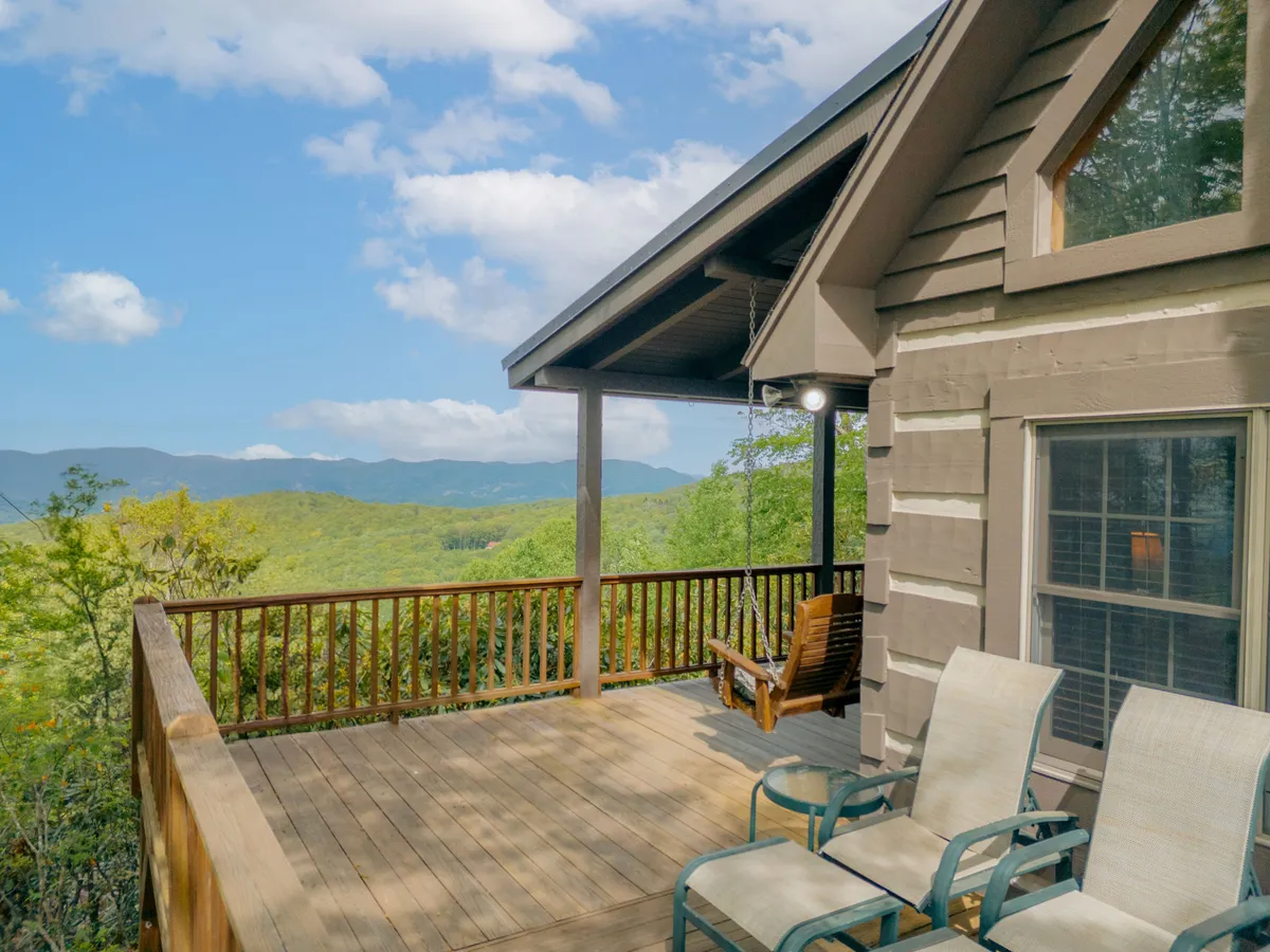 The image showcases a spacious wooden deck with comfortable lounge chairs and a sturdy wooden railing, set against breathtaking long-range mountain views. The scene exudes tranquility, emphasizing opportunities for relaxation, sunrise coffees, stargazing, and outdoor gatherings.