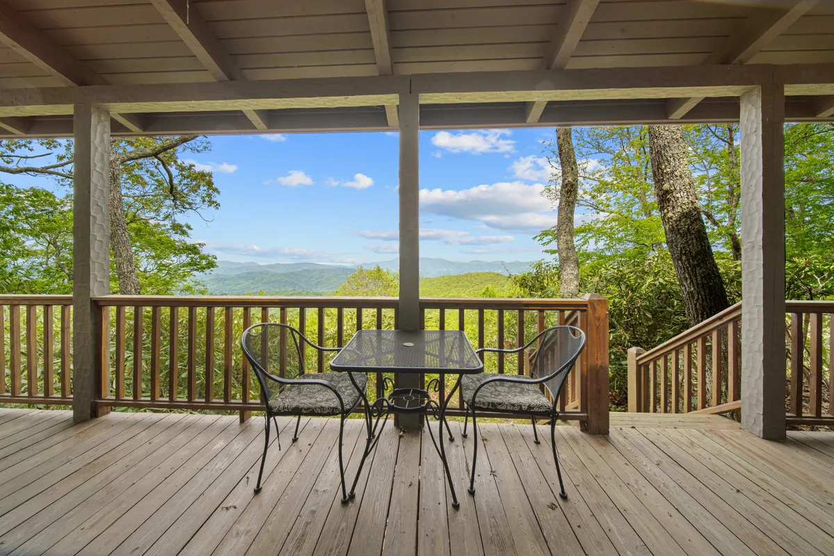 A tranquil scene on the deck with a table and chairs positioned perfectly to take in dramatic mountain views. The wooden railing frames the landscape, and the seating invites guests to relax with a coffee or a book while the sun rises or sets.