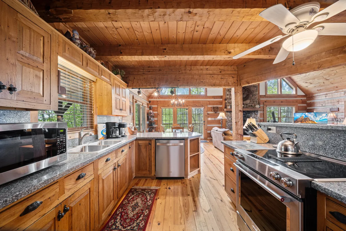 A modern kitchen with rich wooden cabinetry, gleaming granite countertops, stainless steel appliances, and large windows bathing the space in natural light. The open layout shows a smooth transition to adjacent living spaces, ready for preparing feasts and entertaining guests.